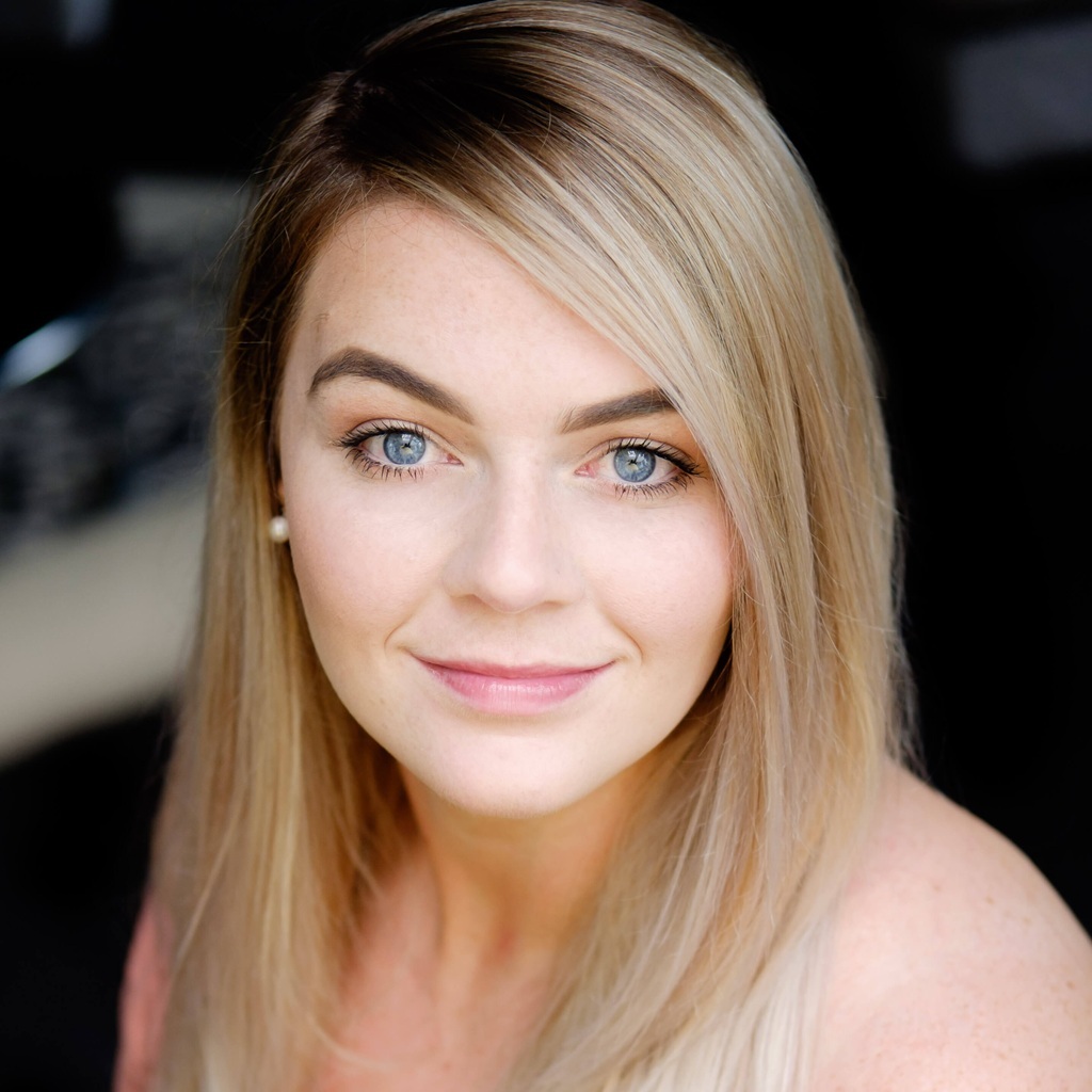 Portrait of Elora H., smiling softly with elegant makeup and hairstyle.