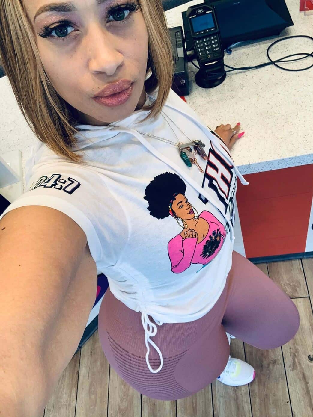 Woman taking a confident selfie in sporty leggings and a printed white hoodie