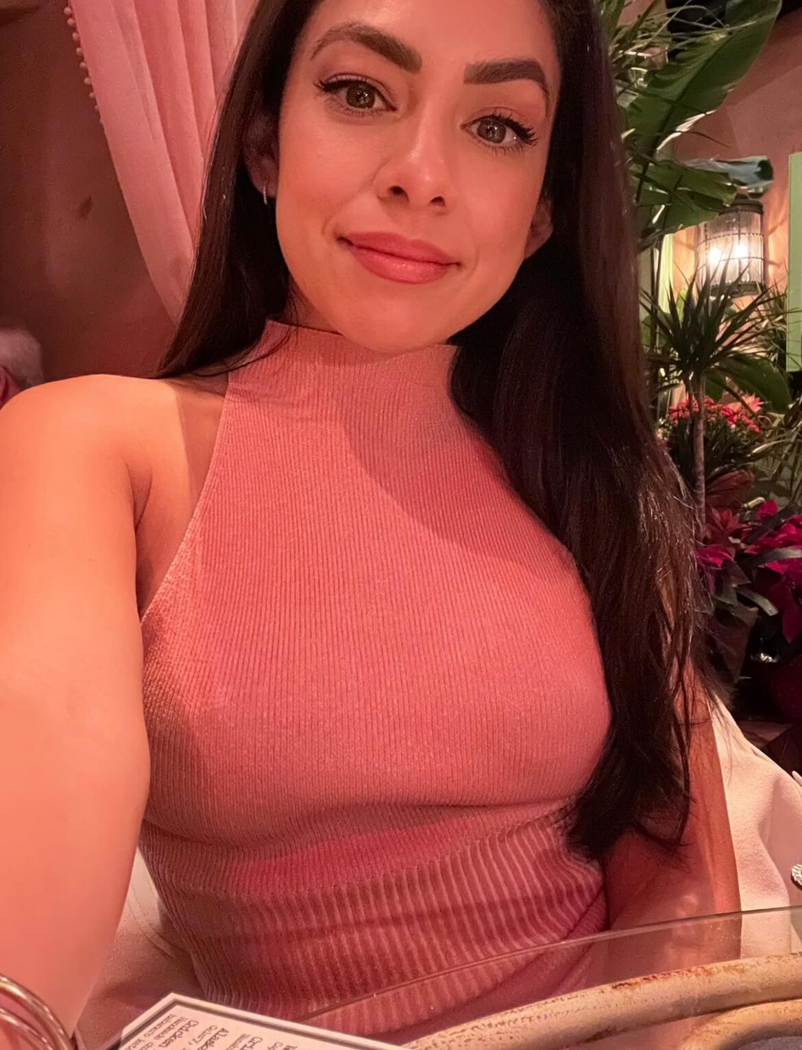 Smiling woman with long dark hair wearing a pink sleeveless top.