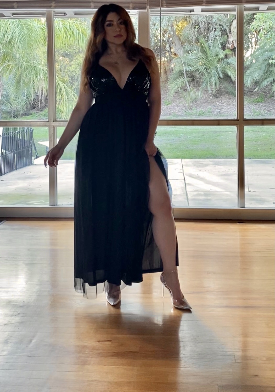 Confident woman posing elegantly in a glamorous evening gown.