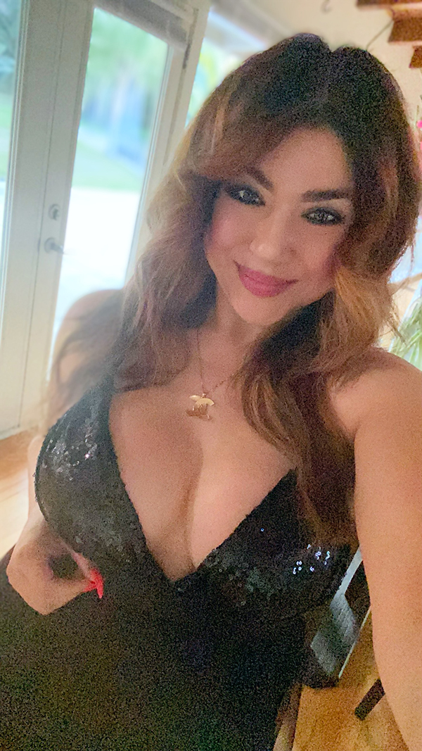 Smiling woman with styled hair wearing a glamorous black sequined dress.