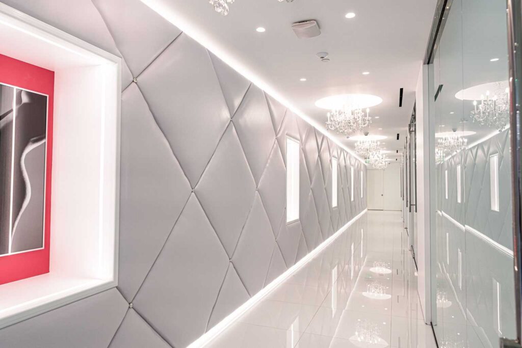 Chandelier corridor with hand-made tufted walls and a recessed art box at Dr. Cat Plastic Surgery, Beverly Hills