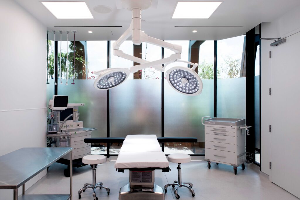 Operating room of the QUAD A accredited surgery center at Dr. Cat Plastic Surgery, with two surgical lights and the operating table