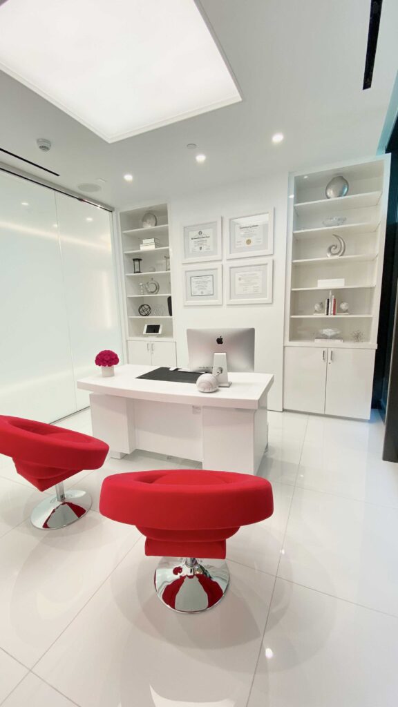 Consultation room with red chairs, a white desk and built-in shelves