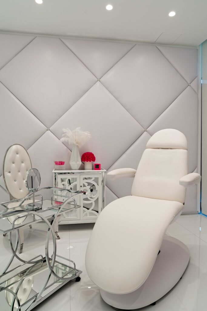 Treatment room with tufted walls, a white treatment chair and a tufted accent chair