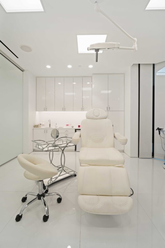 Exam room with a white treatment chair, chrome side table and white cabinets