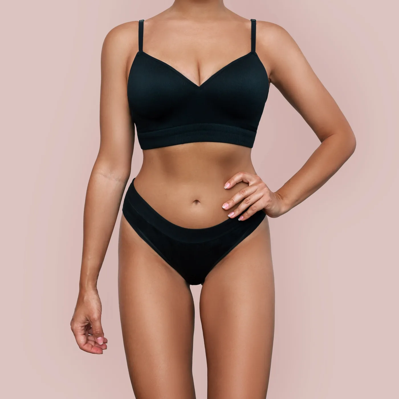 A woman in black underwear against a pink background