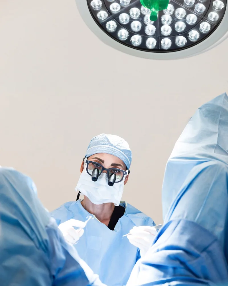 Dr. Cat in surgical cap, mask and gown at the operating table in her Beverly Hills surgery center