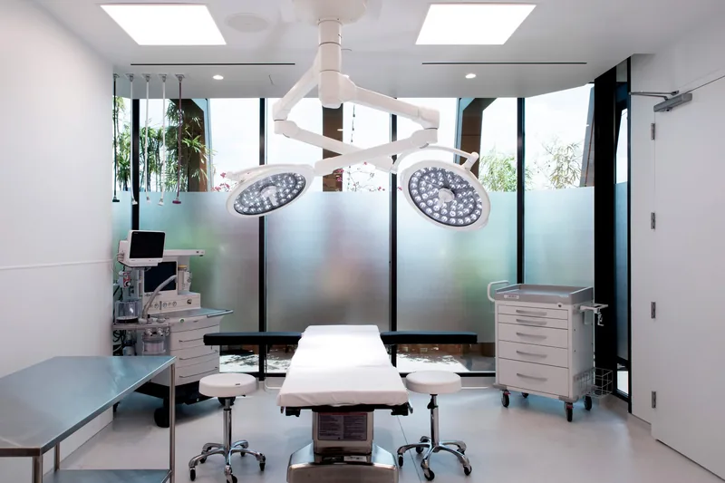 Operating room of the QUAD A accredited surgery center at Dr. Cat Plastic Surgery, with surgical lights and frosted windows